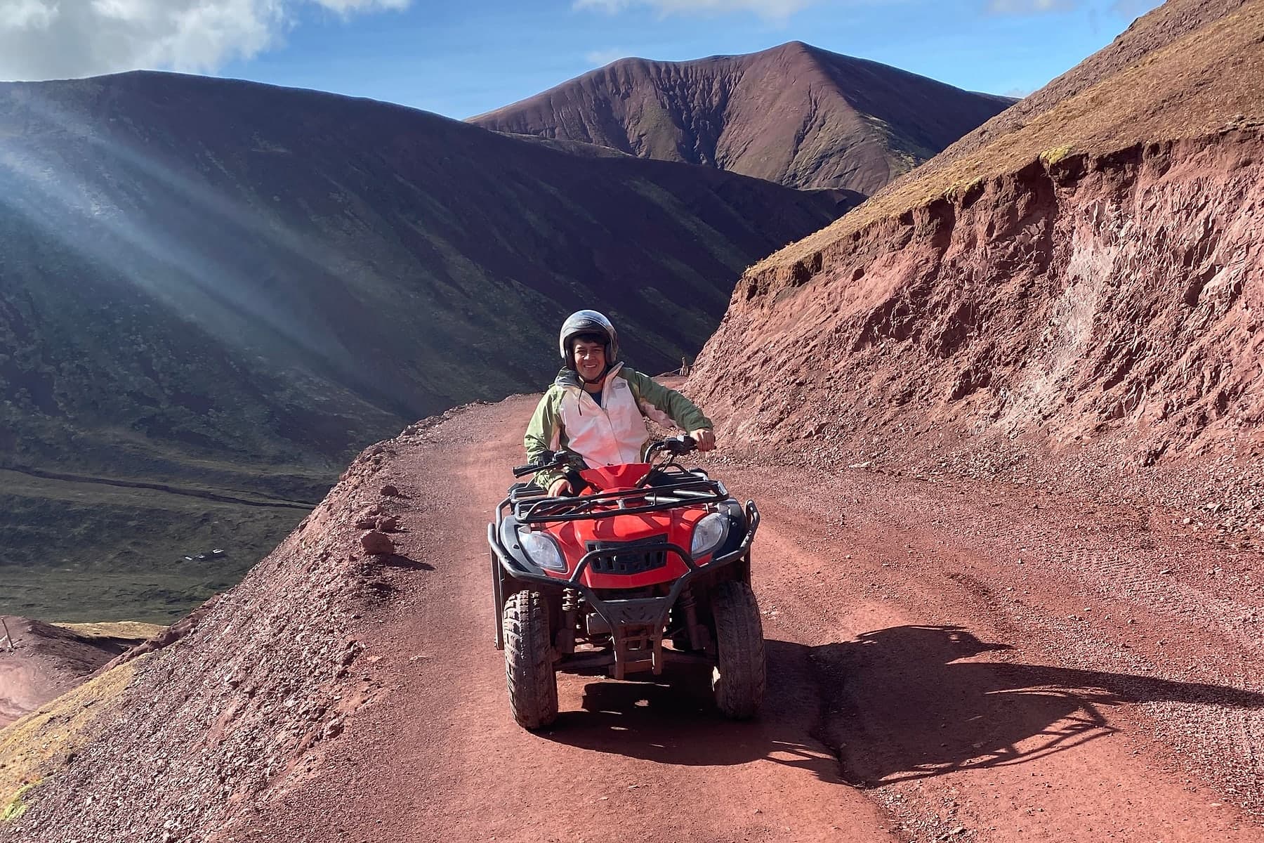 An ATV on the red trail with the coloured slopes of Vinicunca behind