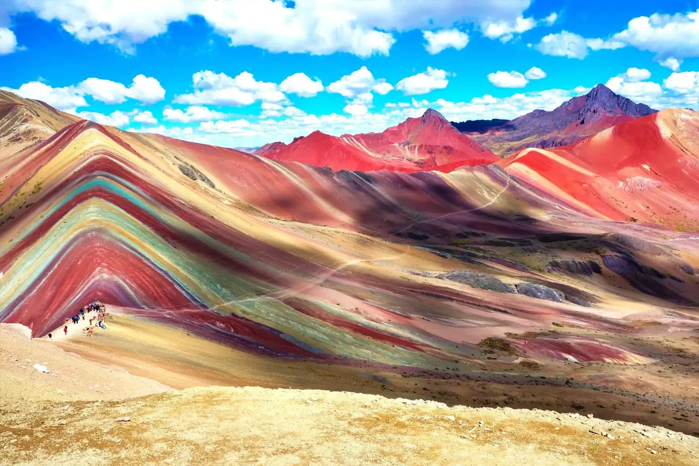 The red and ochre bands of Vinicunca under a deep blue Andean sky